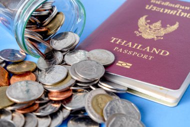 Tayland pasaportu kahverengi kapak ve para sikke üzerinde mavi kağıt arka plan tatil seyahat için