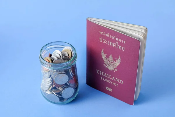 Thailand passport  brown cover and money coin on blue paper background for traveling on holidays