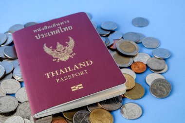 Tayland pasaportu kahverengi kapak ve para sikke üzerinde mavi kağıt arka plan tatil seyahat için