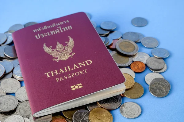 Tailandia pasaporte marrón cubierta y moneda de dinero sobre fondo de papel azul para viajar en vacaciones — Foto de Stock