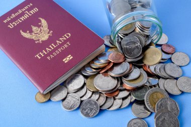 Tayland pasaportu kahverengi kapak ve para sikke üzerinde mavi kağıt arka plan tatil seyahat için