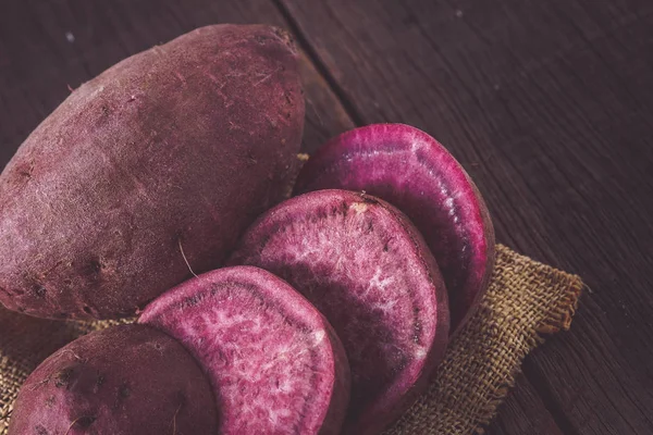 Filtre etkisi retro v ile ahşap arka plan üzerinde ham tatlı patates