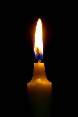 Parlak siyah arka plan üzerine yanan bir mum ışık.