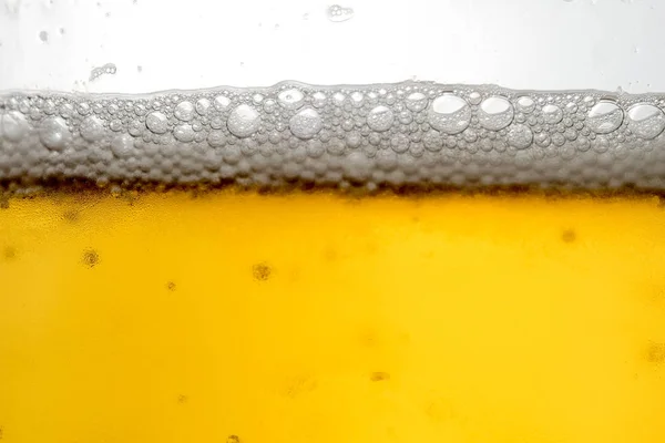 Derramando cerveja com espuma de bolha em vidro para fundo — Fotografia de Stock