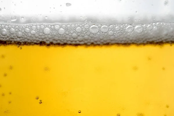 Derramando cerveja com espuma de bolha em vidro para fundo — Fotografia de Stock