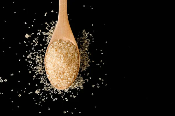 Brown sugar in wood spoon on black background.Components of The