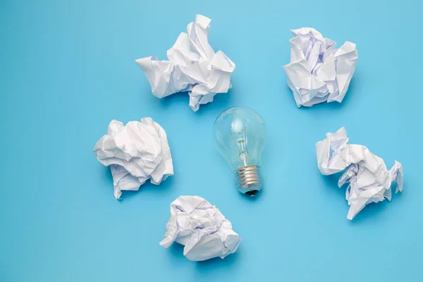 Great concept with crumpled office paper and light bulb on a blue background — Stock Photo, Image