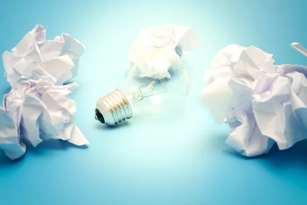 Great concept with crumpled office paper and light bulb on a blue background — Stock Photo, Image