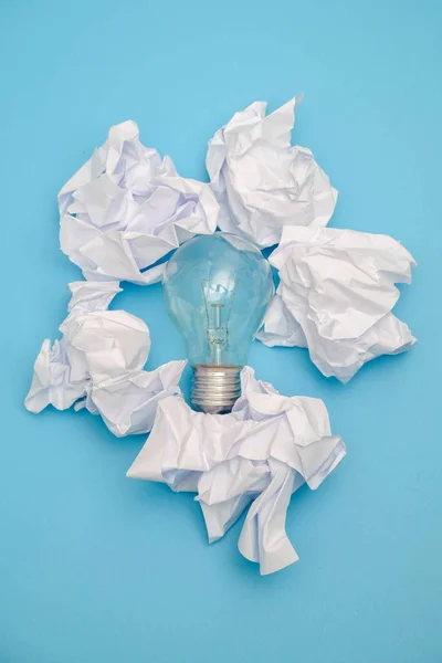 Чудова концепція зі збитим офісним папером та лампочкою на синьому фоні — стокове фото