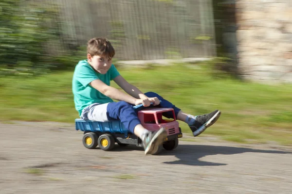 Junge fährt auf Spielzeug-LKW bergab — Stockfoto
