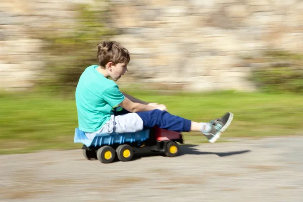 Junge fährt auf Spielzeug-LKW bergab — Stockfoto