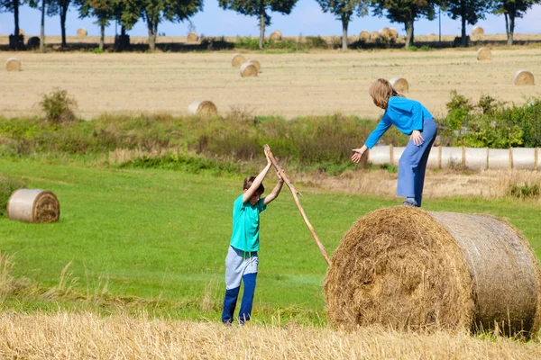 Zwei Jungen bewegen Heuballen mit Stock als Hebel — Stockfoto