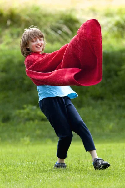 Pojke som springer runt i röd handduk som superhjälte kappa — Stockfoto