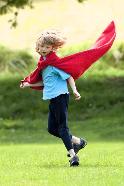 Jongen rondrennen in rode handdoek als superheld mantel — Stockfoto