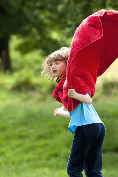 Jongen rondrennen in rode handdoek als superheld mantel — Stockfoto