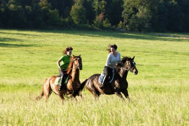 İki kadın bir manzarada binicilik