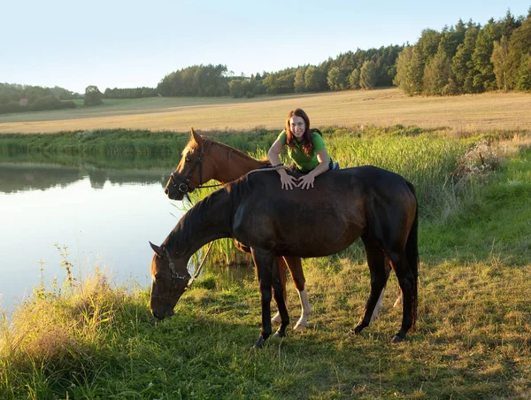 Frau kuschelt mit zwei Pferden am See — Stockfoto