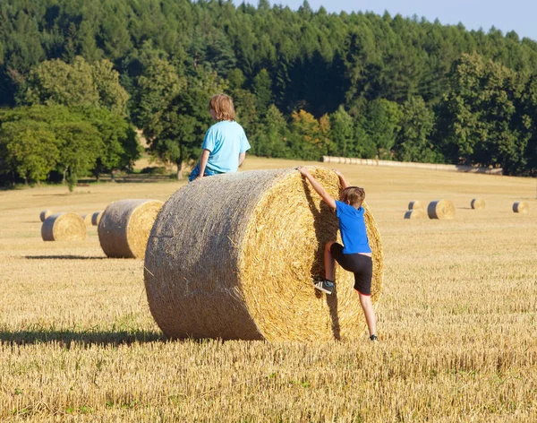 Dva chlapci lezení balík sena — Stock fotografie