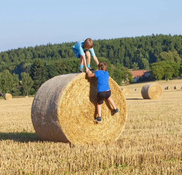 Dva chlapci lezení balík sena — Stock fotografie