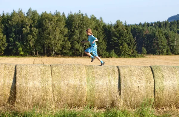 Menino correndo em fardos de Hay — Fotografia de Stock