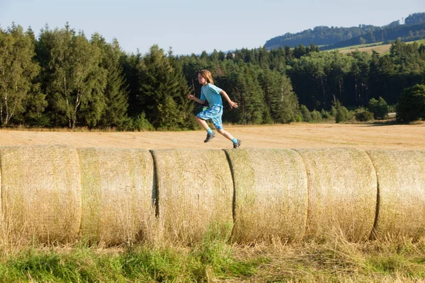 Αγόρι τρέχει σε δεμάτια του σανού — Φωτογραφία Αρχείου