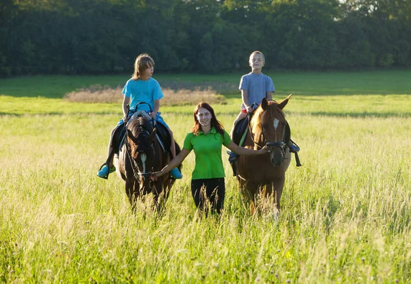 Верховая езда уроки - женщина, ведущая две лошади с мальчиками — стоковое фото