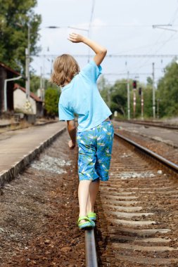 Rayların üzerinde yürürken çocuk