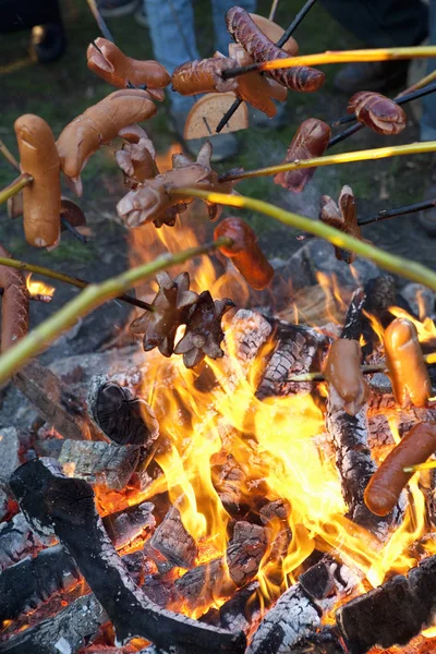 Ihmiset grillaavat makkaroita nuotion ääressä . — kuvapankkivalokuva