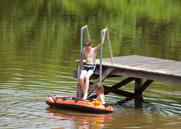 Dois meninos se divertindo com barco de borracha inflável — Fotografia de Stock