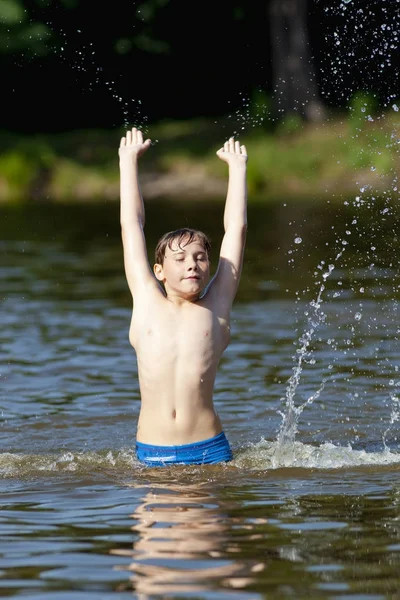 Jongen met plezier Jumping up en opspattend Water — Stockfoto