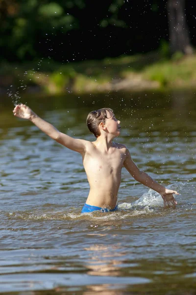 Menino se divertindo pulando e salpicando água — Fotografia de Stock