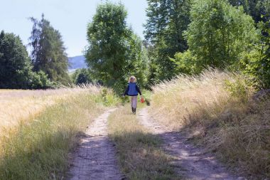 Çocuk bir yolda yürürken bir sepet ile.