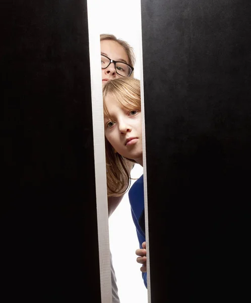 Pareja de niños mirando por detrás de las puertas — Foto de Stock