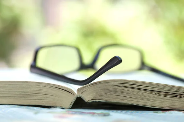 Närbild av glasögon liggande på en öppen bok — Stockfoto