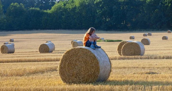 Мальчик, сидящий на тюбике сена летом — стоковое фото