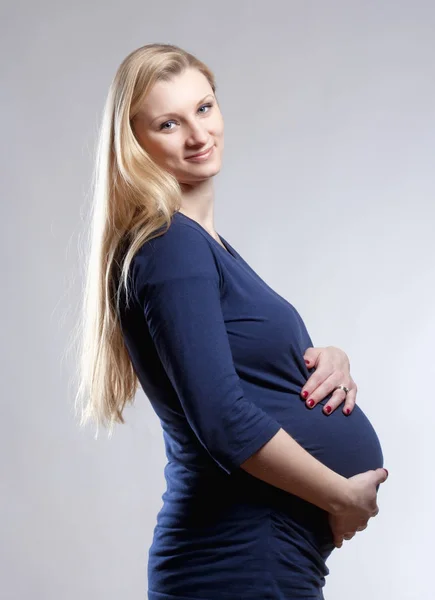 Schwangere blonde Frau im blauen Kleid. — Stockfoto