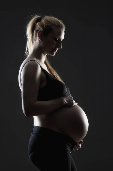 Těhotná blondýna v černé podprsence. — Stock fotografie