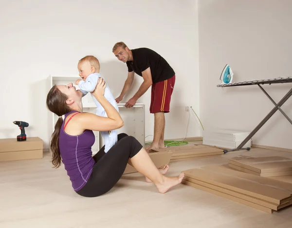 Familia joven con un bebé mudándose a un apartamento nuevo — Foto de Stock