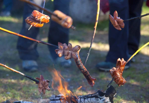 Persone che grigliano salsicce sul fuoco . — Foto Stock