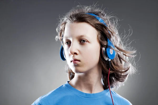 Niño con el pelo castaño escuchando música en auriculares . — Foto de Stock