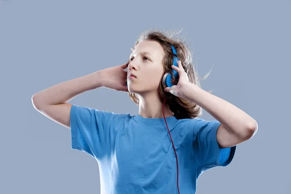 Niño con el pelo castaño escuchando música en auriculares . — Foto de Stock