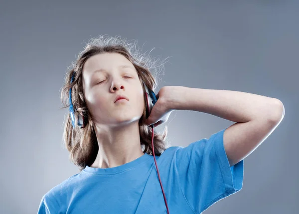 Niño con el pelo castaño escuchando música en auriculares . — Foto de Stock