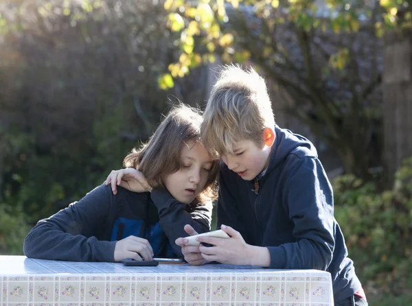 정원에 휴대 전화를 가지고 있는 두 소년. — 스톡 사진