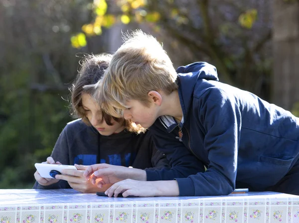 Dos chicos con teléfonos móviles en el jardín . —  Fotos de Stock