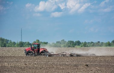 Tarlada çalışan traktör, modern bir tarımsal ulaşım, verimli arazi, arazi ekimi, tarım makinesi.