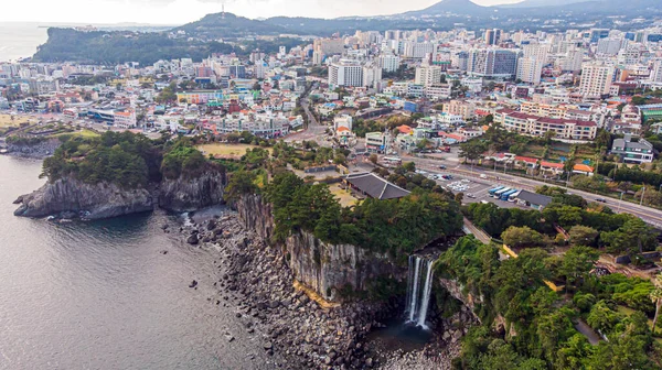 Aerial View of The High Waterfall Jeongbang, Lagoon and Seoqwipo on Jeju Island, South Korea.