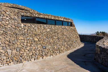 Modern Kamu Mimarisi. Taştan yapılmış eğimli duvar. Güneşli bir günde Kaya Barakası.