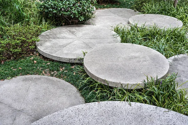 Round Concrete Steps in the Small Garden. Pathway Between Bushes. Landscape Design of Sustainable Green Architecture. Stepping Stones at Greenery.