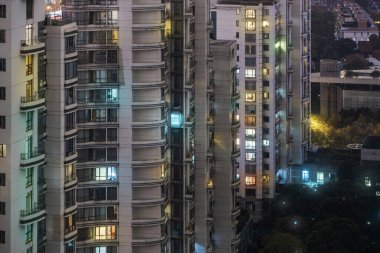 Gece vakti Highrise 'ın yakın çekim görüntüsü. Renkli Aydınlatılmış Pencereler. Shanghai, Çin 'deki Konut Binaları ve Bahçesi.