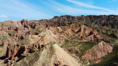 Gökkuşağı Dağları Jeolojik Parkı 'nın Havadan Görünümü. Stripy Zhangye Danxia Landform Jeoloji Parkı, Gansu Eyaleti, Çin. Güneşli bir günde, Vadideki Yoldaki Turist Otobüslerinin İnsansız Hava Aracı.